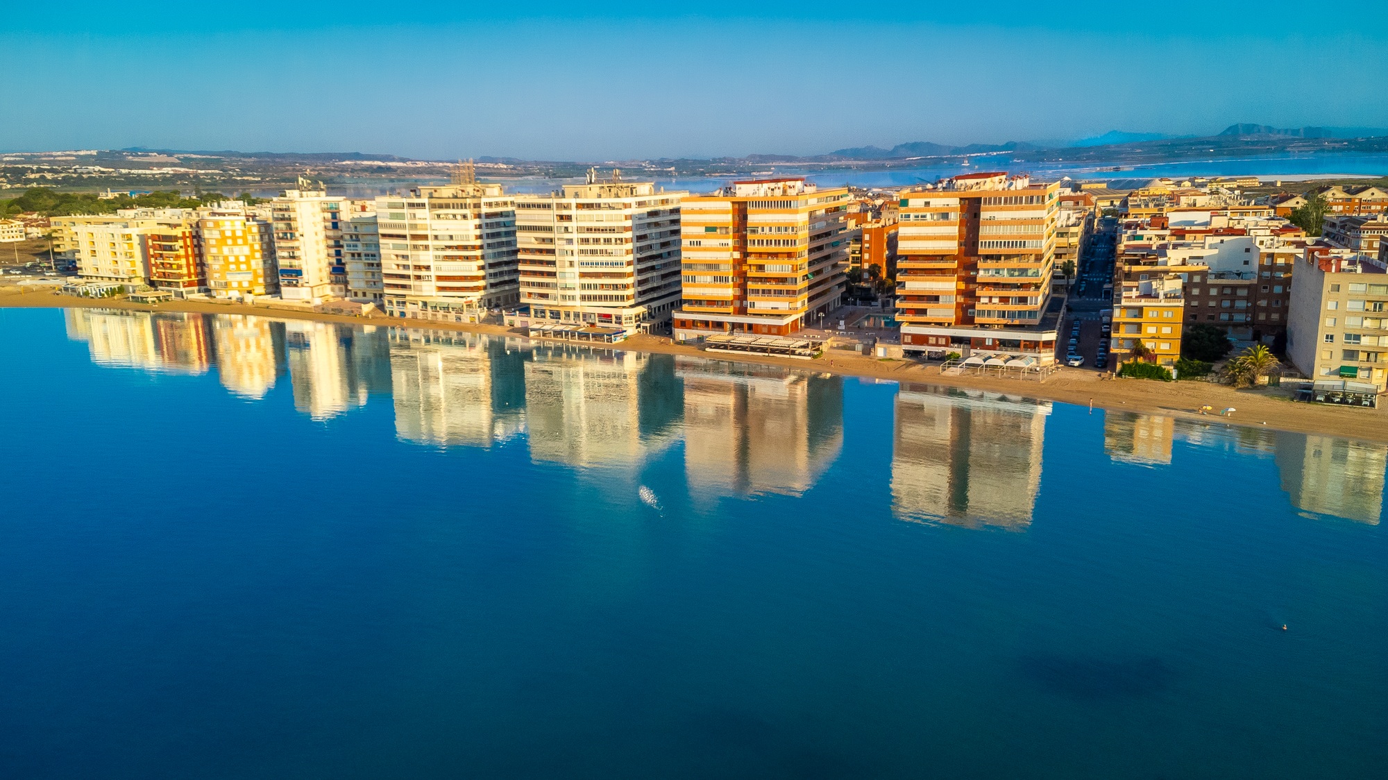 Torrevieja skyline reflecting on calm mediterranean sea at sunrise